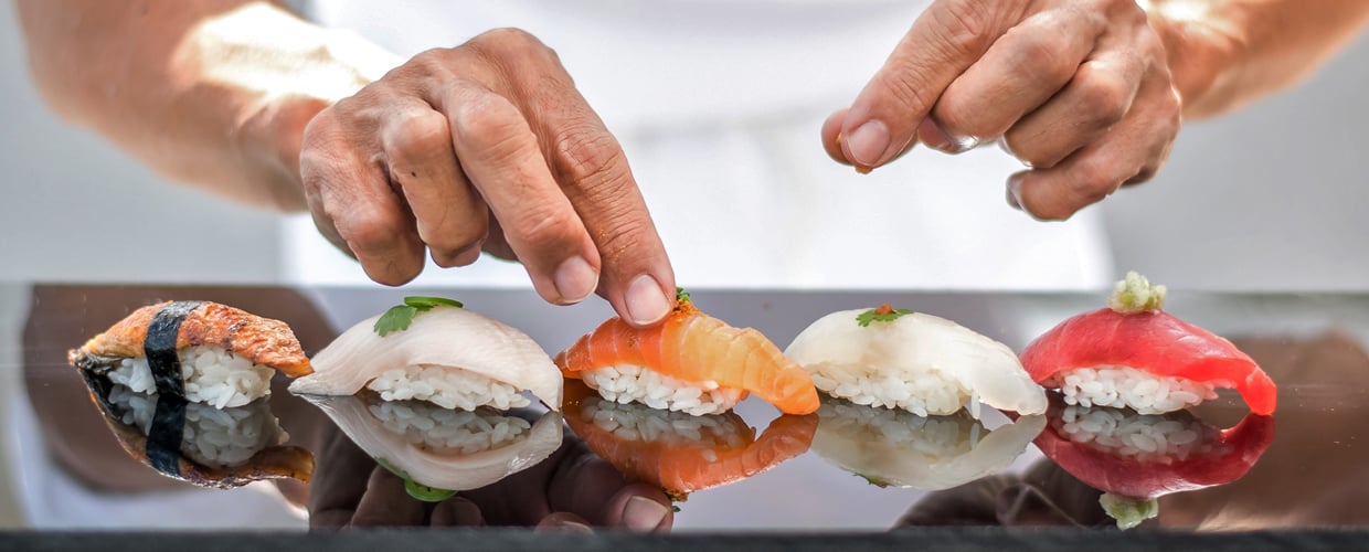hands placing garnish on sushi